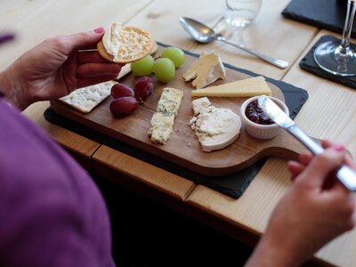 Over-shoulder view of cheeseboard and grapes enjoyed in well-lit Hassness House dining room