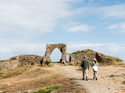 Couple exploring Grosnez walking towards historic ruin, Les Landes, Jersey