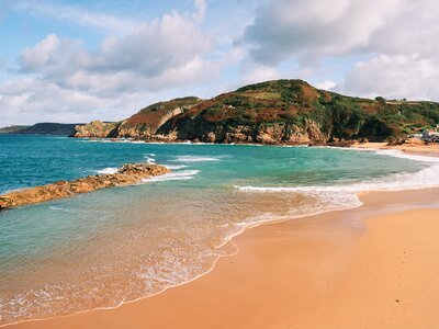 Light tides breaking on golden sand beach on sunny day with cloudy sky, Greve de lecq, St Ouen, Jersey
