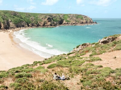 Two people sat enjoying view of beach in Plemont on sunny day, St Ouen, Jersey