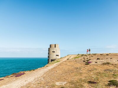 Hikers walking towards German fortification on coast, Gronez, Jersey