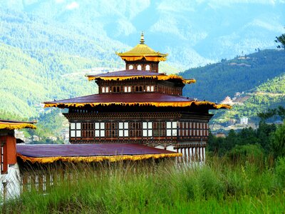 Close view of Tashichho Dzong buddhist monastery and fortress building with tall green grass growing along border in foreground, on the northern edge of the city of Thimphu in Bhutan, on the western bank of the Wang Chu