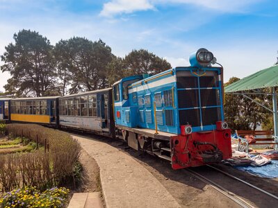 Famous Toy train of the Darjeeling Himalayan railway with view of tourists at Batasia loop in West Bengal, India