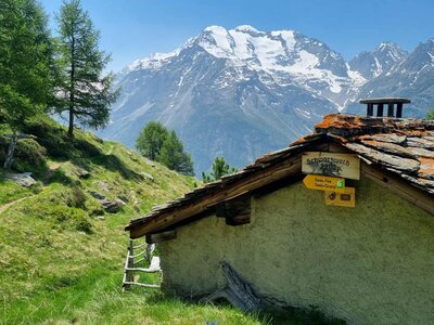 Traditional swiss house in mountains with saas fee and saas grund walking and hiking trail signage, Switzerland 