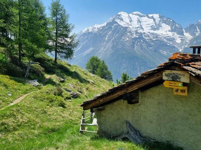Traditional swiss house in mountains with saas fee and saas grund walking and hiking trail signage, Switzerland 