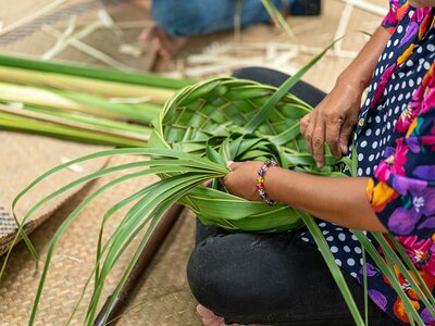 Close up of person using traditional craftsman technique for coconut leaf weaving to create a hat