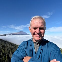 Ramble Worldwide walking holiday leader Tom Hanna in Tenerife with Mount Teide in the background sitting above the clouds and pine forests