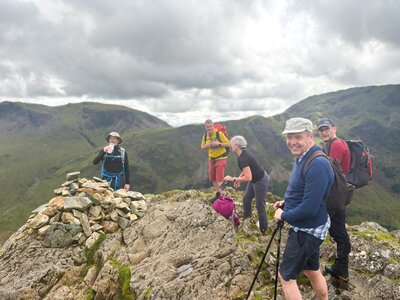 Ramble Worldwide walking group atop summit in the Lake District bagging a wainwright peak with walk leader Tom Hanna