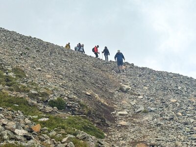 Ramble Worldwide walking group descending from summit after bagging an Alfred Wainwright peak in the Lake District, Cumbria, England, United Kingdom