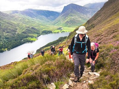Ramble Worldwide walking group on walking holiday in the Lake District ascending rocky trail to bag a Wainwright peak