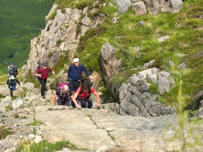 Ramble Worldwide walking group scrambling upwards, Lake District, Cumbria, England, United Kingdom