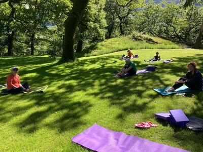 Women sat on yoga mats in lake district at hassnness house on ramble worldwide holiday womens activity week