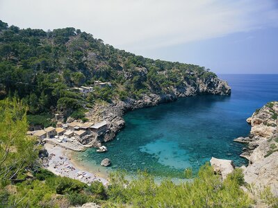 Distant view of coastal beach with houses nearby, Cala de Deia, Mallorca, Spain