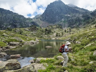 Woman using walking poles along footpath next to Juclar Lake, Estanys de Juclar, Andorra, Europe