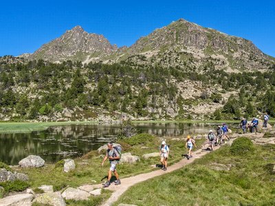 Line of walkers on Ramble Worldwide walking holiday descending path near Pessons Lakes on sunny day, Andorra, Europe