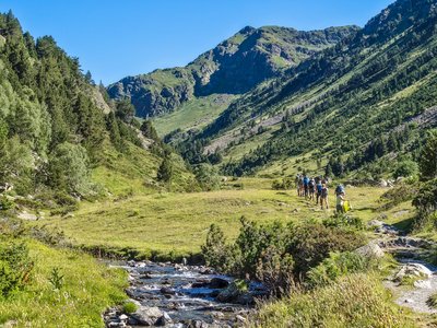 Hikers passing through green mountainous landscape of The Rialb Valley on walking holiday adventure with Ramble Worldwide, Andorra, Europe