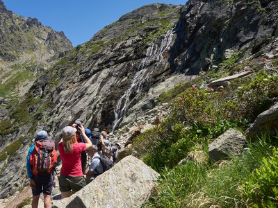 Group of walkers pausing on walking break with one woman taking picture of mountainside, Col de Juclar, Andorra, Europe