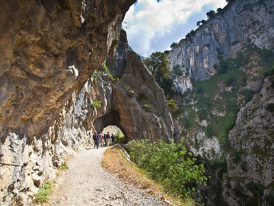 Walking holiday group walking through archway in Cares Gorge from Cain, Picos De Europa, Spain