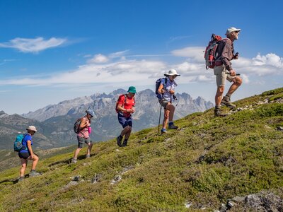 Side view of walking group on walking holiday ascending green hill in Spanish mountain range Picos De Europa 