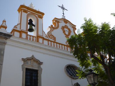 Low-to-high view of church bell and cross viewed from outside building, Algarve, Portugal