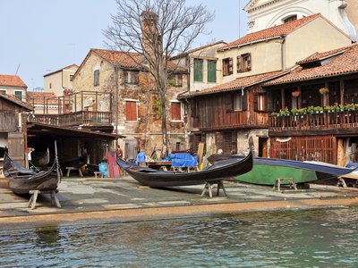 Gondola yard with traditional venetian houses surrounding boats near canal, Venice, Italy