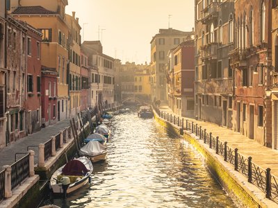Canal in Venice with sun shining brightly onto traditional venetian houses, Italy