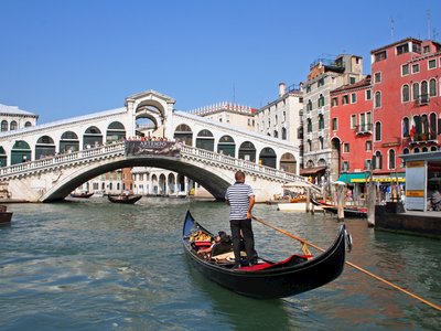 Man steering gondola nearing Rialto Bridge, Venice, Italy