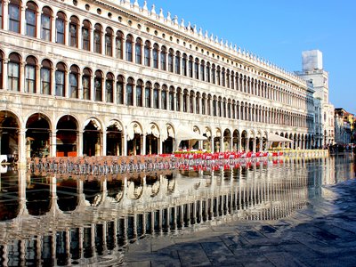 Procuratie Vecchie, Basilica di San Marco and clocktower are reflected in water (Acqua alta) of St. Mark's Square, Venice, Italy