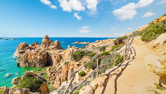 Coastal pathway in Costa Paradiso with view of blue sea and large rocks jutting out close to trail, Sardinia, Italy