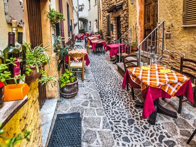 Rustic tables along alleyway restaurants in Castelsardo old town, Sardinia, Italy