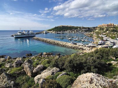 Mgarr Harbour with many boats docked up and town in far distance, south-eastern Gozo, Malta