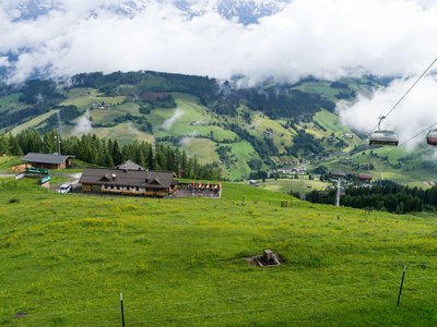 Alpine hut mountain restaurant and cable car on mountainside viewed from above
