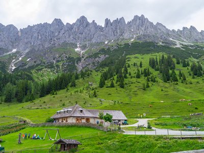 House at bottom of mountain range with sharp-edge mountain ridges at higher altitude in background, Austria